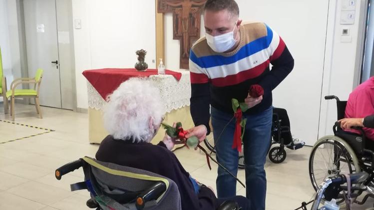 Il neo presidente dell'Ipab, Andrea Bassi, consegna una rosa a un'ospite del centro Anziani (Madinelli)