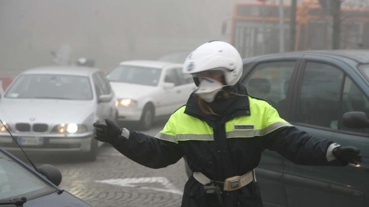 Agente della polizia municipale in mezzo al traffico si protegge dallo smog con una mascherina   