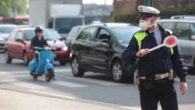 Un vigile con la mascherina in mezzo al traffico