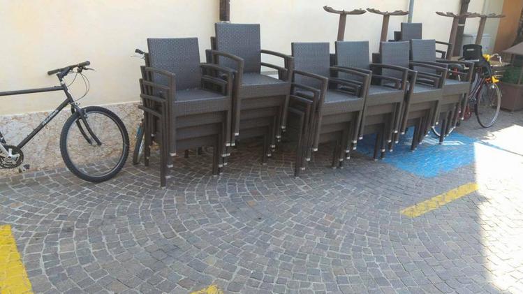 Le sedie accatastate sul parcheggio per i disabili