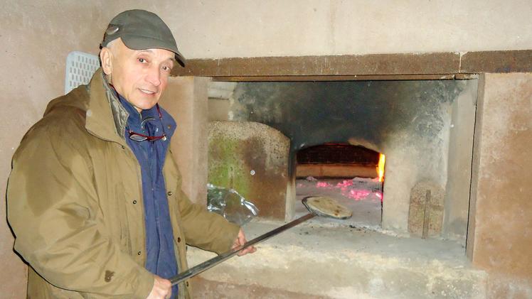 Un volontario di «Adige Nostro»  infila  il pane nel forno della villa 