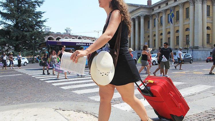 Turisti italiani stranieri con i trolley in piazza Bra. La tassa di soggiorno garantisce al Comune quasi 4 milioni di euro