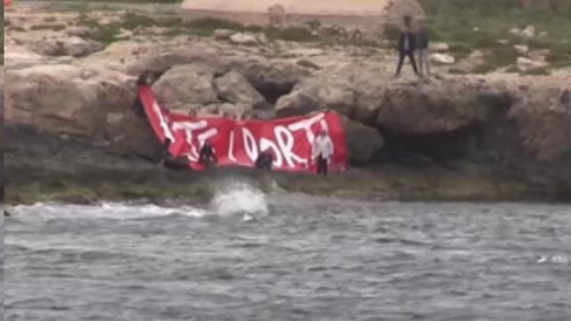 "Aprite i porti" hanno scritto alcuni attivisti in uno striscione esibito vicino alla porta d'Europa, nella costa di Lampedusa. Il messaggio è ben visibile dalla nave Mare Jonio che stazione davanti all'isola. di Giorgio Ruta