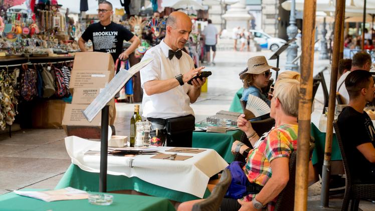 I negozi in centro città saranno aperti anche oggiAlcuni turisti vengono serviti nei locali in piaza Erbe