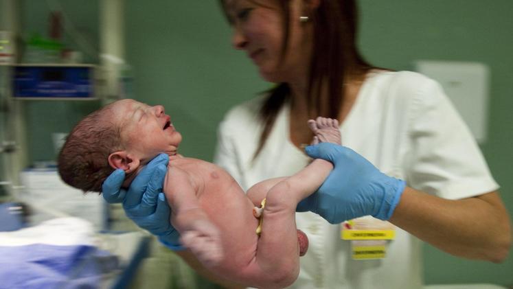 Un neonato in braccio ad un'ostetrica