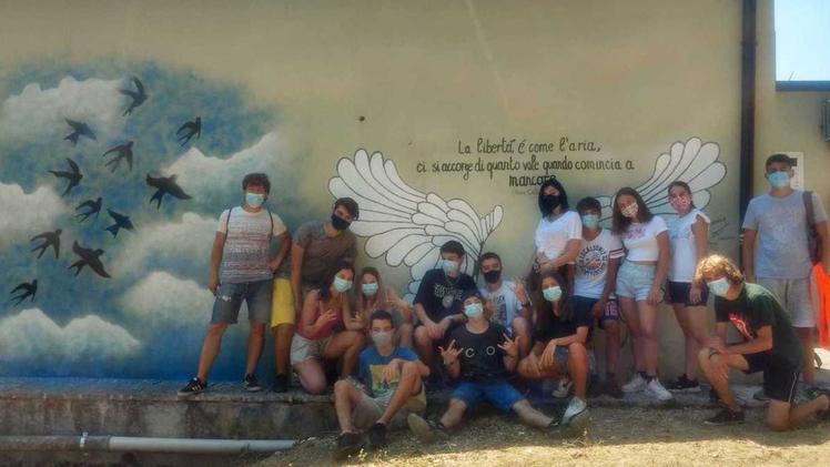 Due ragazze impegnate a scrivere sul murale  la frase di Piero Calamandrei Il murale realizzato dai ragazzi sul muro della scuola media a Castelnuovo