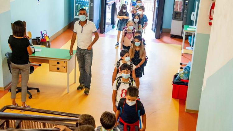 Bambini in fila con la mascherina entrano a scuola