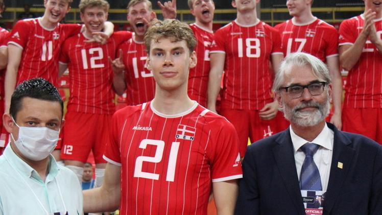 Mads Jensen premiato come Mvp all’European Silver League dove la Danimarca ha vinto l’oro. Sullo sfondo la gioia dei compagni di squadra