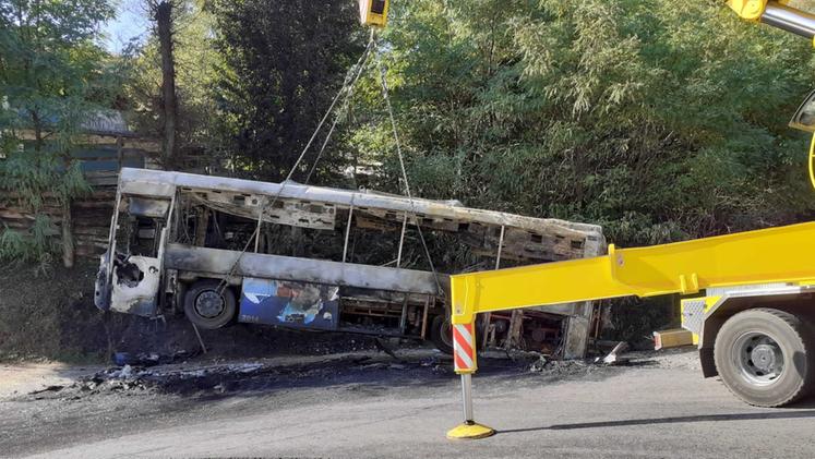 Lo scheletro bruciato del bus caricato su un rimorchio