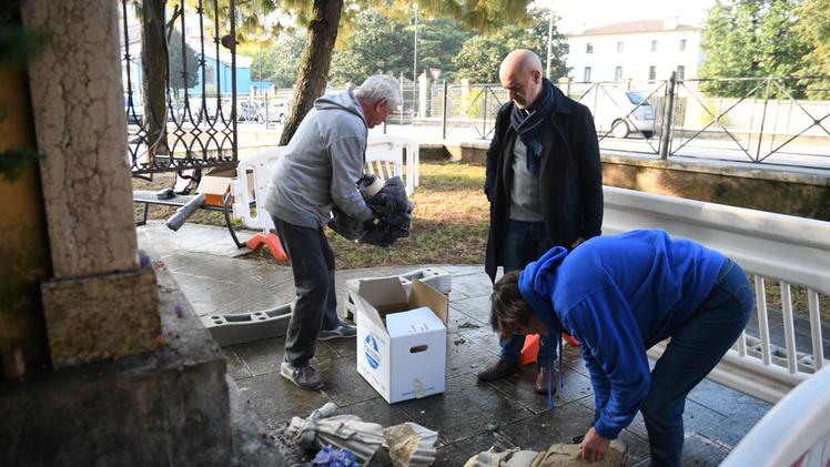 Il parroco, restauratrice e un volontario raccolgono i pezzi della statua distrutta. Il sindaco ha già disposto la recinzione del sito