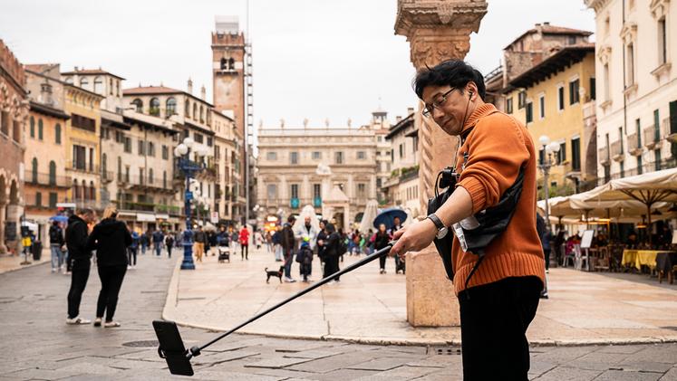 Piazza Erbe - Un turista alle prese con un selfie "estremo" (foto Marchiori)
